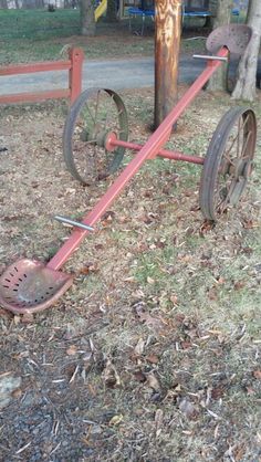 an old wheelbarrow leaning against a pole in the grass next to a tree