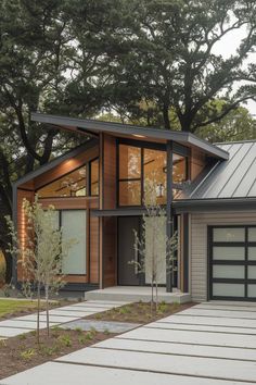 a modern house with two garages and trees in the background