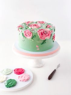 a green cake with pink roses on it and some icing next to the cake