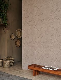 a wooden bench sitting in front of a wall with baskets on it and a potted plant next to it