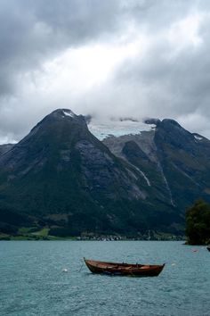 a boat floating on top of a lake next to mountains