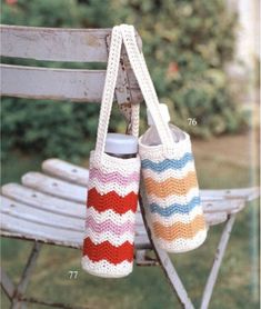 two crocheted purses hanging from a bench