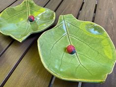 two green plates with ladybugs on them sitting on a wooden table next to each other