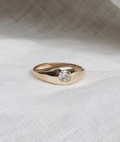 a gold ring sitting on top of a white cloth with a diamond in the middle