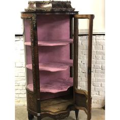 an old wooden cabinet with purple velvet on the shelves