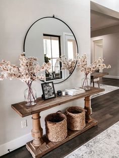 there is a mirror and some flowers on the shelf in front of the console table