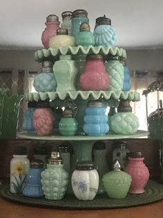 there are many glass jars on the shelf in front of each other and one is blue, green, pink