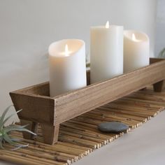 three lit candles sit on a wooden tray