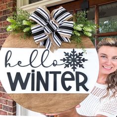 a woman standing next to a sign that says hello winter