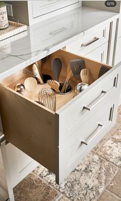 an open drawer with utensils in it on a countertop next to a sink