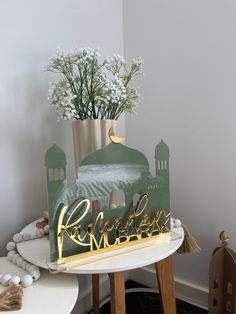 a table with a sign that says rama on it and flowers in a vase next to it