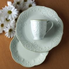 two tea cups and saucers with daisies in the background