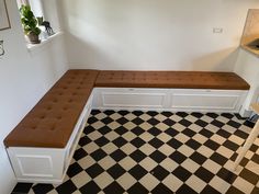 a kitchen with black and white checkered flooring and a bench in the corner