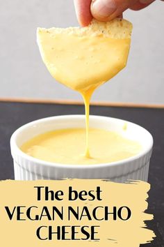 the best vegan nacho cheese sauce in a small white bowl with a hand dipping it