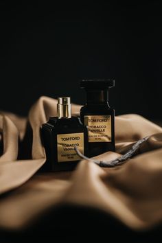 two bottles of perfume sitting on top of a blanket