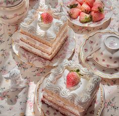 there are three pieces of cake on the table with strawberries and teacups