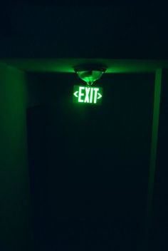 exit sign lit up in the dark with green light coming from it's side