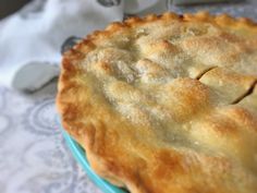 a pie sitting on top of a blue plate next to a white cloth covered table