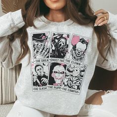 Step Into The Spookiest Season Of The Year With Our Halloween Fright Night Tarot Card Sweatshirt, The Perfect Blend Of Comfort And Eerie Style. Each Sweatshirt Is Meticulously Designed, Featuring Iconic Horror Characters The Slasher, The Camper, The Clown, Ghost Face, The Puppet, And The Dreamer Portrayed In A Uniquely Mystic Style On Tarot Cards. Available In A Variety Of Eerie Colors And A Broad Range Of Sizes. Perfect Blend Of Comfort And Halloween Spirit. A Great Conversation Starter For Any Mystic Style, Halloween Fright Night, The Slasher, Recycled Sweaters, The Puppet, Ghost Face, Fright Night, The Clown, Horror Characters