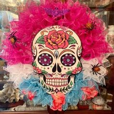 a sugar skull with pink and blue ruffles on it's head in a display case