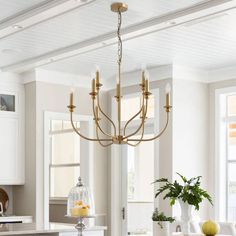 a chandelier hanging from the ceiling in a white and gray kitchen with an island