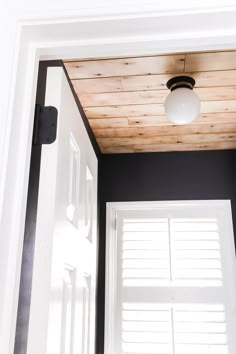 the light is on above the door in the room that has black walls and white trim