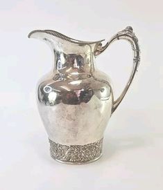 an antique silver pitcher is shown on a white background