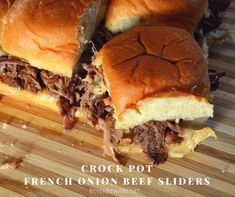 two sandwiches cut in half sitting on top of a wooden cutting board with the words crock pot french onion beef sliders