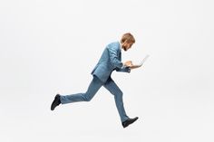 a man in a blue suit is running with a laptop computer on his lap top