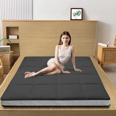 a woman sitting on top of a bed in a room with wooden floors and furniture