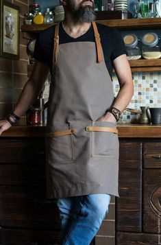 a man wearing an apron standing in front of a kitchen counter with his hands on his hips