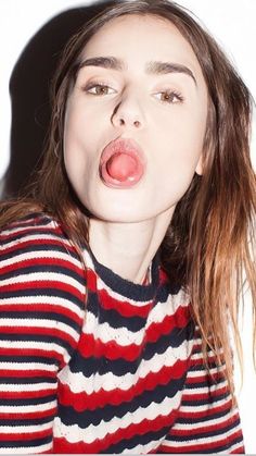 a woman making a funny face with her tongue out and eyes wide open, wearing a striped shirt