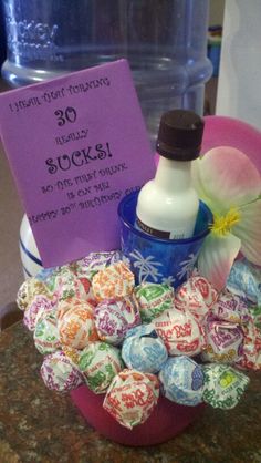 a basket filled with lots of candy next to a bottle of water and a sign