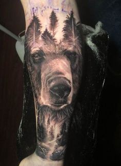 a man's arm with a bear and trees tattoo on the left side of his leg