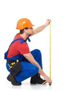 a man in overalls and an orange helmet is holding a measuring tape