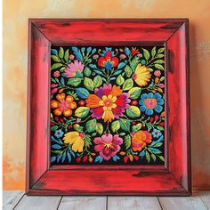 a painting with flowers painted on it in a red frame