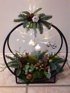 a christmas tree with lights and greenery in a circular display case on a tile floor