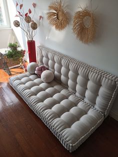 a white couch sitting on top of a hard wood floor next to a vase filled with flowers