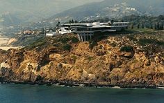 a large house on top of a cliff by the ocean