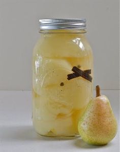 a glass jar filled with liquid next to a pear