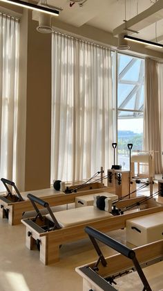 an empty gym with rows of rowing bikes and exercise equipment in front of large windows