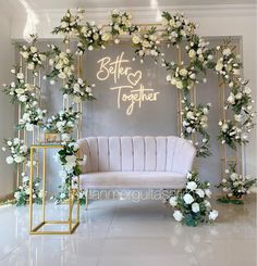 a white couch sitting in front of a wall with flowers and greenery on it