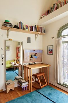 a room with a desk, bookshelf and window