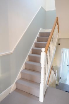 there is a white stair case next to the carpeted stairs in this house with light blue walls