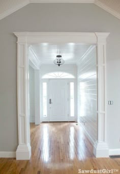 an empty hallway leading to a white door and light fixture in the center of the room