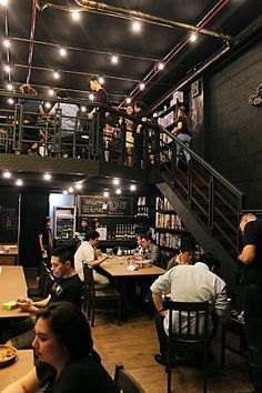 people are sitting at tables and eating in a restaurant with lots of bookshelves