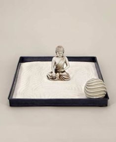 a small buddha statue sitting on top of a white tray next to a round object