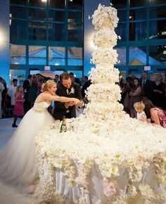 the bride and groom are cutting their wedding cake at the reception in front of an audience