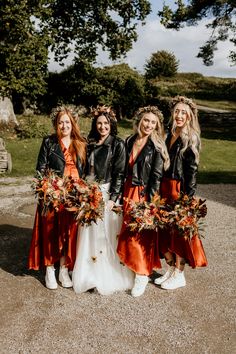 the bridesmaids are dressed in orange dresses and black leather jackets with floral crowns on their heads