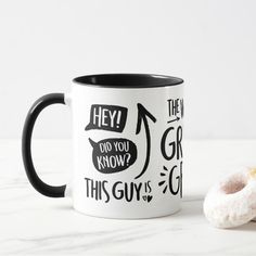 two donuts sitting next to each other on a white table with black and white coffee mugs